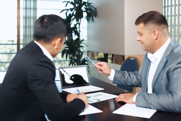 Portrait of two business partners sitting at a table together and working.