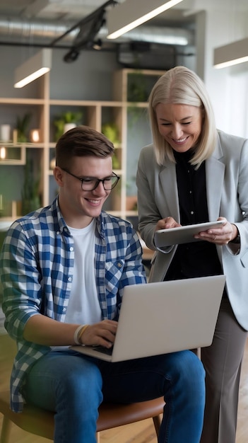 Photo portrait of two creative colleagues smiling and discussing work using laptop and tablet in office