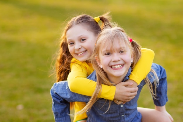 Photo portrait of two happy cute girls outdoors in the park, children having fun