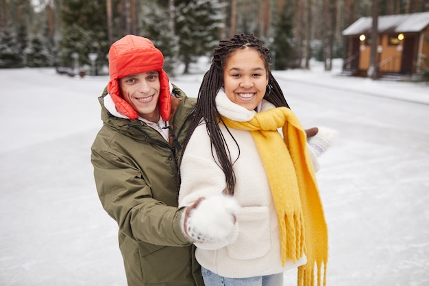 Portrait of two happy friends smiling at camera while standing outdoors in winter day