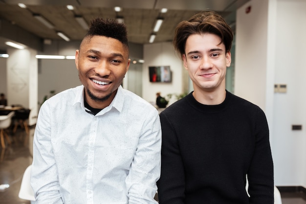 Portrait of two happy handsome students in library.