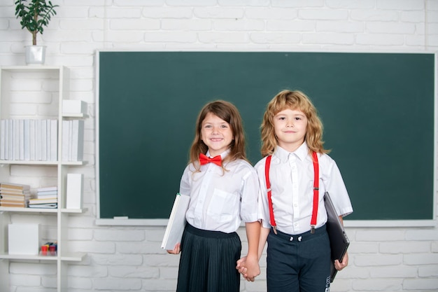 Portrait of two happy school kids studying in classroom at elementary school concept of friendship a