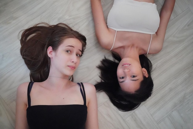 Portrait of two interracial best friends girls lying on floor and smiles