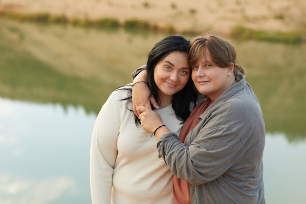 Portrait of two lesbians embracing each other and looking at camera while walking on the nature