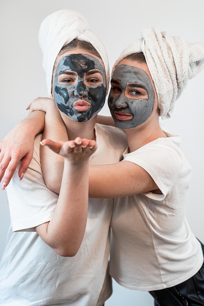 Portrait of two sister or girlfriend make skin facial mask isolated on white Anti age care relax concept