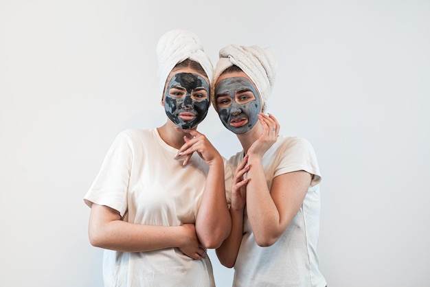 Portrait of two sister or girlfriend make skin facial mask isolated on white