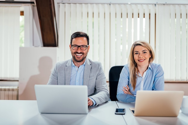 Portrait of a two successful business people in coworking office. Looking at camera.