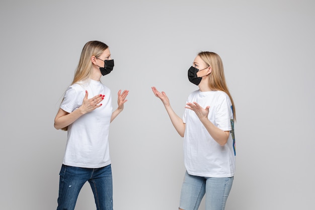 Photo portrait of two teenage girls with long fair hair with black medical masks