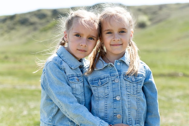 Portrait of two twin sisters who embrace in a meadow in nature