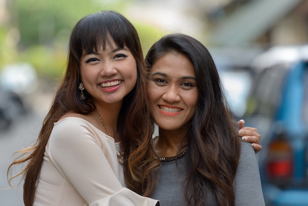 Portrait of two young Asian businesswomen together in the city outdoors