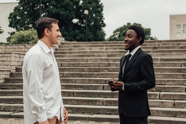 Portrait of two young confident businessmen going down the stairs and talking