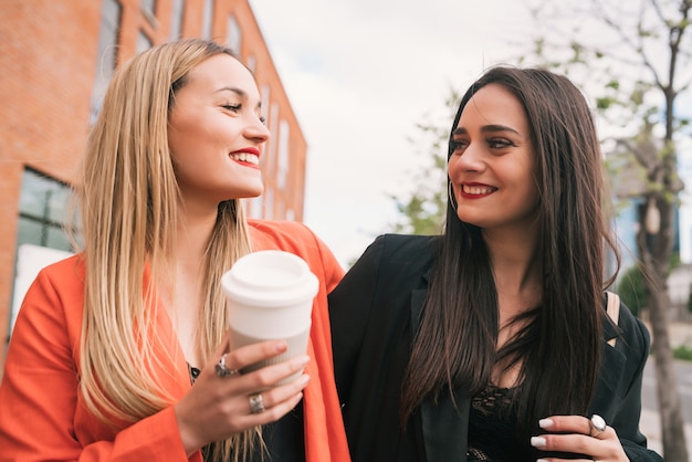 Portrait of two young friends spending good time together while walking outdoors at the street