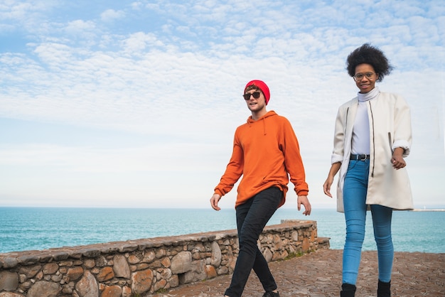 Portrait of two young friends spending some nice time together, walking on coast line and having fun