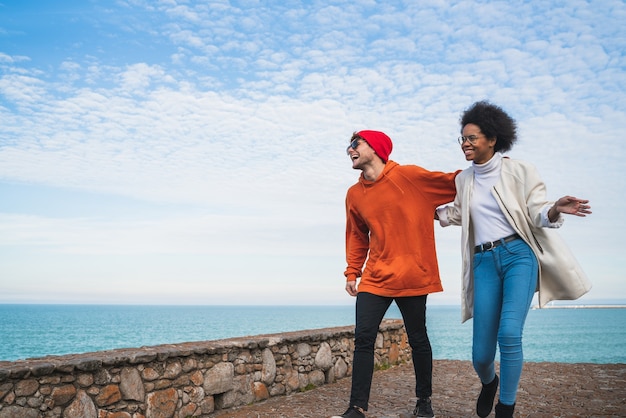 Portrait of two young friends spending some nice time together, walking on coast line and having fun.