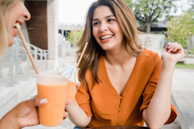 Photo portrait of two young friends spending time together at a coffee shop outdoors