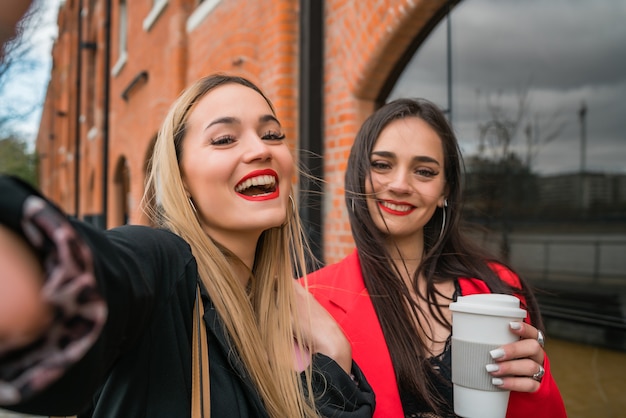 Portrait of two young friends taking a selfie outdoors at the street