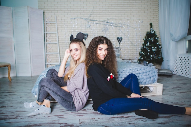 Portrait of two young women near a decorated Christmas tree New Year's Eve A bright festive image of two sisters Merry Christmas