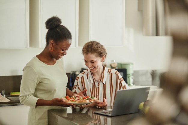 Portrait of two young women sharing meal in cozy home kitchen copy space