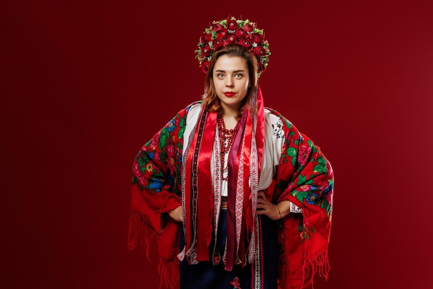 Portrait of ukrainian woman in traditional ethnic clothing and floral red wreath on viva magenta studio background Ukrainian national embroidered dress call vyshyvanka Pray for Ukraine