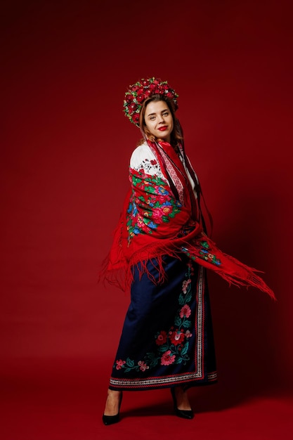 Portrait of ukrainian woman in traditional ethnic clothing and floral red wreath on viva magenta studio background Ukrainian national embroidered dress call vyshyvanka Pray for Ukraine