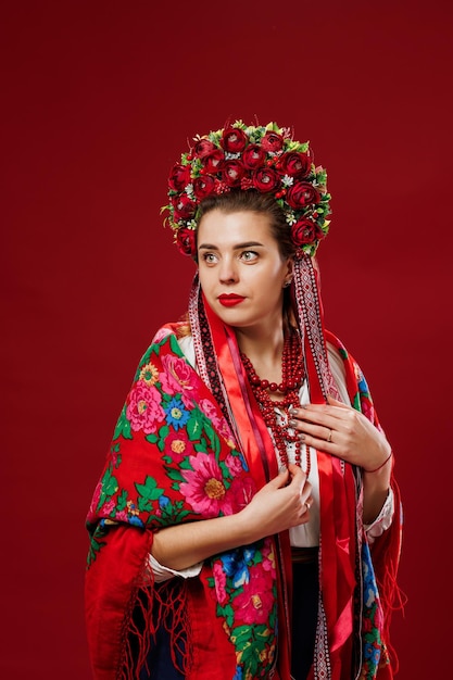 Portrait of ukrainian woman in traditional ethnic clothing and floral red wreath on viva magenta studio background Ukrainian national embroidered dress call vyshyvanka Pray for Ukraine