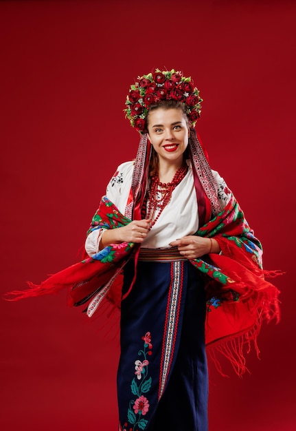 Portrait of ukrainian woman in traditional ethnic clothing and floral red wreath on viva magenta studio background Ukrainian national embroidered dress call vyshyvanka Pray for Ukraine