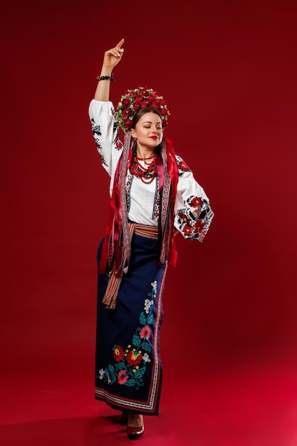 Portrait of ukrainian woman in traditional ethnic clothing and floral red wreath on viva magenta studio background Ukrainian national embroidered dress call vyshyvanka Pray for Ukraine