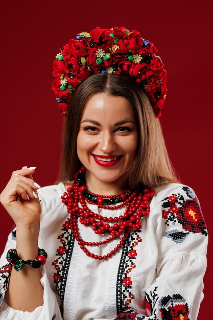 Portrait of ukrainian woman in traditional ethnic clothing and floral red wreath on viva magenta studio background Ukrainian national embroidered dress call vyshyvanka Pray for Ukraine