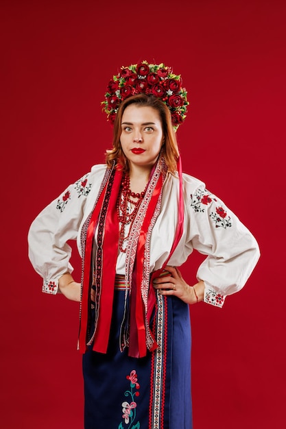 Portrait of ukrainian woman in traditional ethnic clothing and floral red wreath on viva magenta studio background Ukrainian national embroidered dress call vyshyvanka Pray for Ukraine