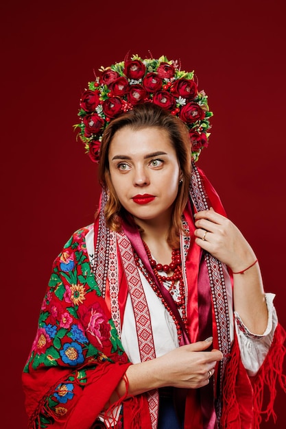 Portrait of ukrainian woman in traditional ethnic clothing and floral red wreath on viva magenta studio background Ukrainian national embroidered dress call vyshyvanka Pray for Ukraine