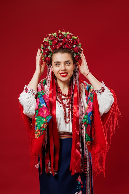 Portrait of ukrainian woman in traditional ethnic clothing and floral red wreath on viva magenta studio background Ukrainian national embroidered dress call vyshyvanka Pray for Ukraine