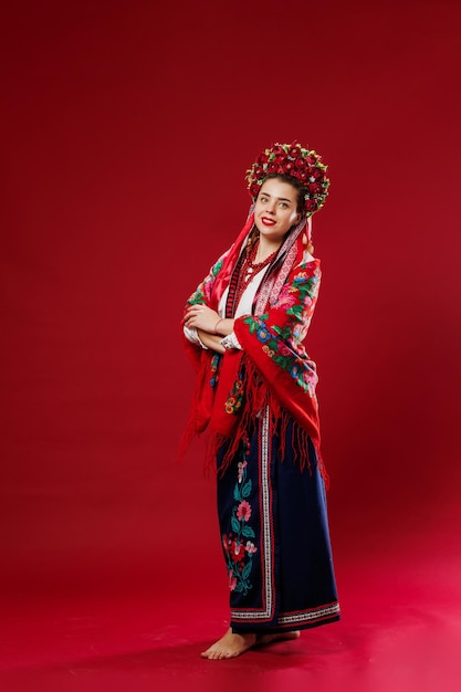 Portrait of ukrainian woman in traditional ethnic clothing and floral red wreath on viva magenta studio background Ukrainian national embroidered dress call vyshyvanka Pray for Ukraine