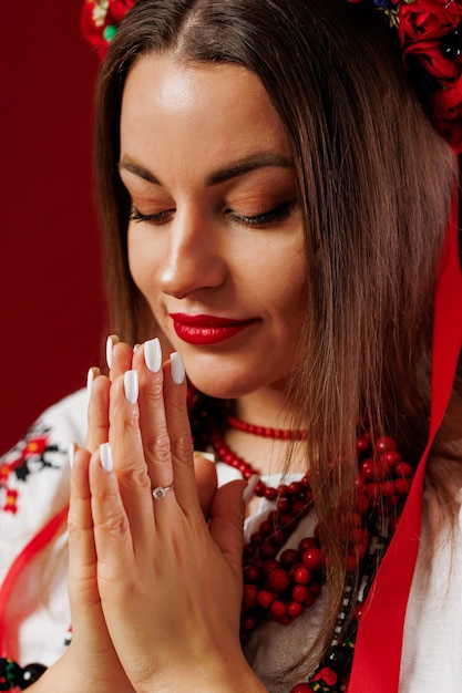 Portrait of ukrainian woman in traditional ethnic clothing and floral red wreath on viva magenta studio background Ukrainian national embroidered dress call vyshyvanka Pray for Ukraine