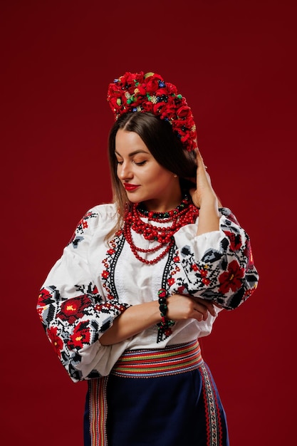 Portrait of ukrainian woman in traditional ethnic clothing and floral red wreath on viva magenta studio background Ukrainian national embroidered dress call vyshyvanka Pray for Ukraine