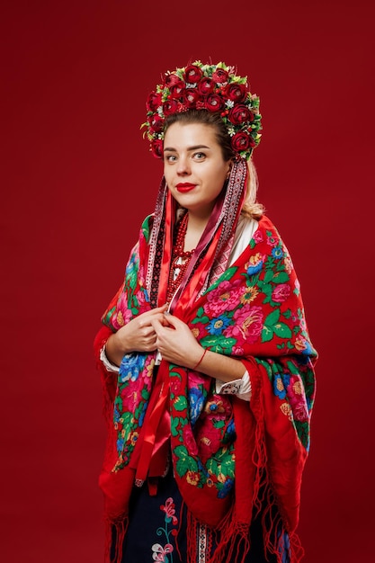 Portrait of ukrainian woman in traditional ethnic clothing and floral red wreath on viva magenta studio background Ukrainian national embroidered dress call vyshyvanka Pray for Ukraine