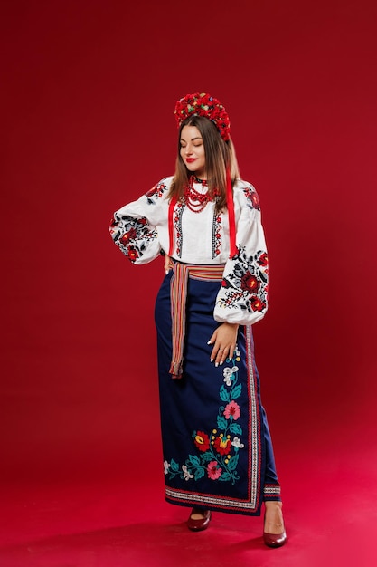 Portrait of ukrainian woman in traditional ethnic clothing and floral red wreath on viva magenta studio background Ukrainian national embroidered dress call vyshyvanka Pray for Ukraine