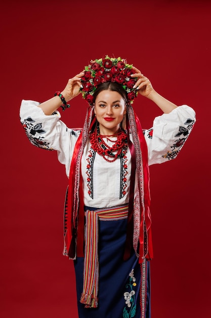 Portrait of ukrainian woman in traditional ethnic clothing and floral red wreath on viva magenta studio background Ukrainian national embroidered dress call vyshyvanka Pray for Ukraine