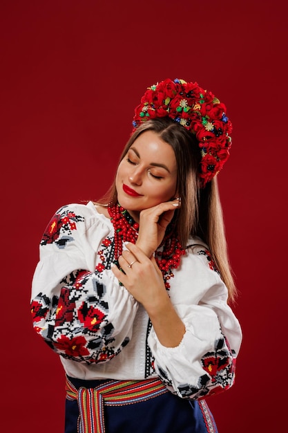 Portrait of ukrainian woman in traditional ethnic clothing and floral red wreath on viva magenta studio background Ukrainian national embroidered dress call vyshyvanka Pray for Ukraine