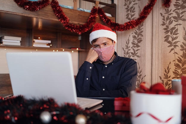 Portrait of unhappy man in mask sitting in room near christmas decorations