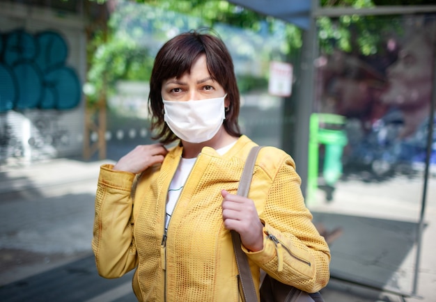 Portrait of an unidentified young woman in a mask posing outdoors during a coronovirus pandemic on a sunny warm summer day