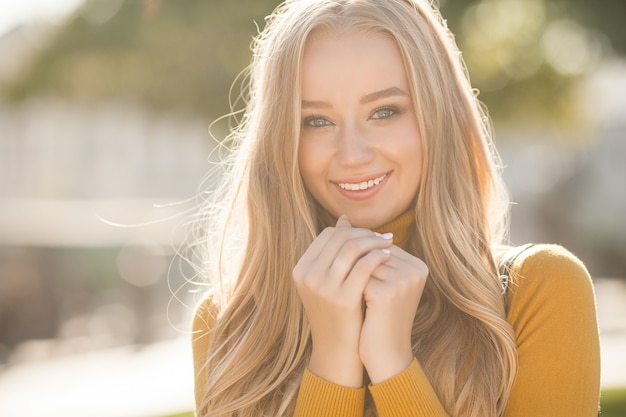 Portrait of very attractive young woman outdoor. Beautiful blond lady at urban background. Stylish female closeup portrait.