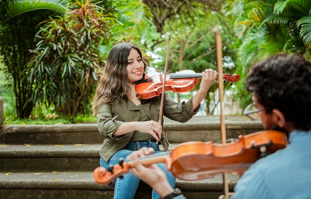 Portrait of violinist people sitting on stairs playing violin Portrait of two young violists playing violin sitting on stairs outside Man and woman sitting on the stairs playing a melody with violin