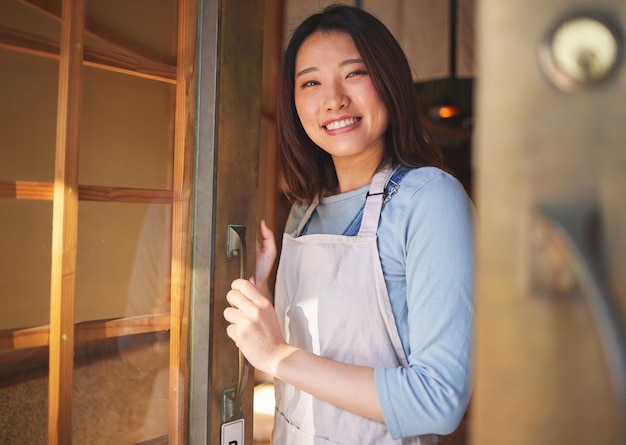 Portrait waitress and Asian woman at door of restaurant coffee shop or retail store Face smile or confident barista happy employee or small business entrepreneur welcome to cafe startup in Japan