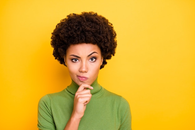 portrait of wavy brown haired interested woman grimacing touching chin with curiousity on face .