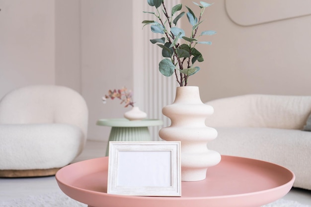 Portrait white picture frame mockup on table. Modern ceramic vase. Scandinavian interior.