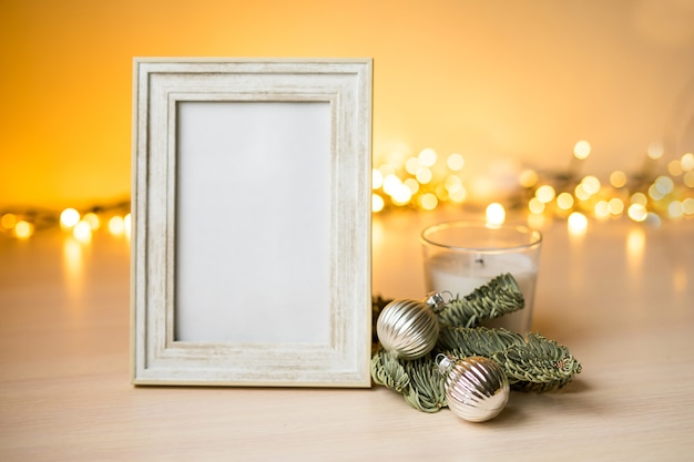 Portrait white picture frame mockup on table with boken lights and christmas decoration. High quality photo