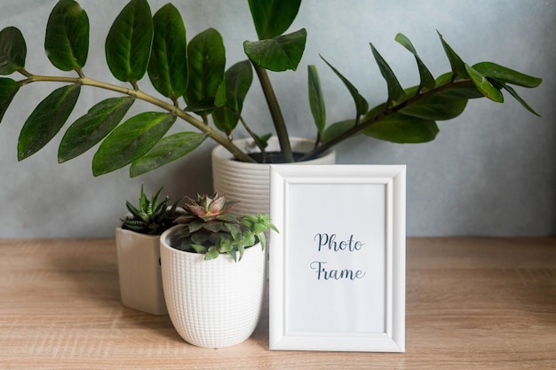 Portrait white picture frame mockup with white pots with succulents and zamiokulkas