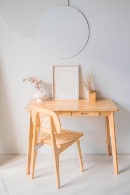 Portrait white picture frame mockup on wooden table. Modern ceramic vase with eucalyptus.