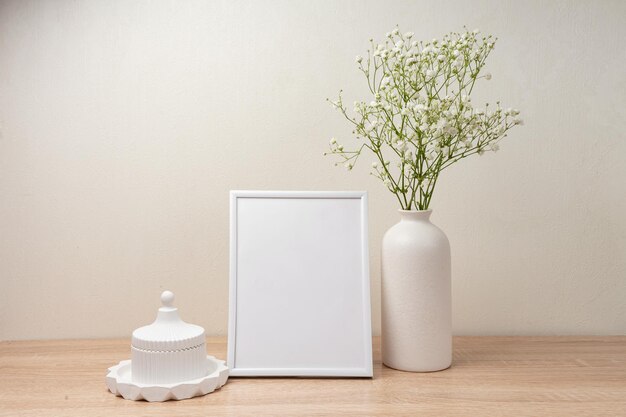 Portrait white picture frame mockup on wooden table modern ceramic vase with gypsophilascandinavian