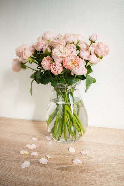 Portrait white picture frame mockup on wooden table Modern ceramic vase with roses White wall background Scandinavian interior